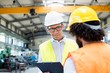 © moodboard - Male supervisor discussing with manual worker in metal industry