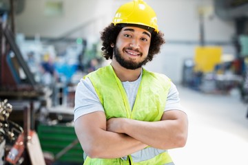 Wall Mural - Portrait of smiling male manual worker standing arms crossed in industry