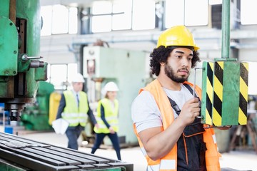 Wall Mural - Young manual worker operating machinery in metal industry