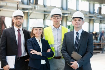 Wall Mural - Team of confident business people wearing hardhats in metal industry