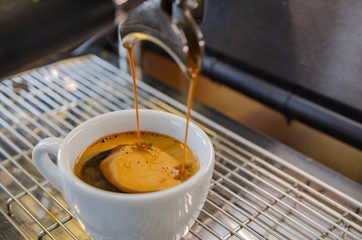 Barista is creating black coffee at the coffee machine.