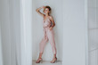 portrait of a beautiful fashionable blonde woman in a pink jumpsuit on a white background