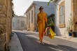 © MEM Studio/Stocksy - Woman in yellow dress is holding shopping bags