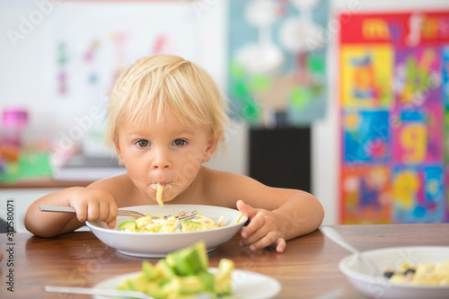 Cuadros en Lienzo Sweet toddler boy, eating spaghetti at home, making a mess and having fun