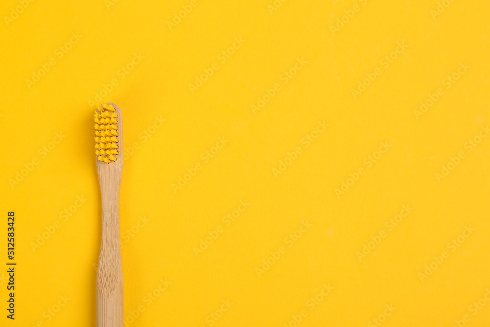 Toothbrush made of bamboo on yellow background, top view. Space for ...