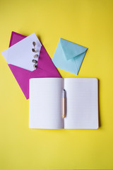 Wall Mural - Opened notebook and colorful envelopes with note blank on the yellow background. Background with copy space.