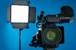 © New Africa - Professional video camera and lighting equipment on blue background, closeup