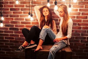 two teenage girl friends together having fun in modern loft interior with holiday lights, lifestyle people concept