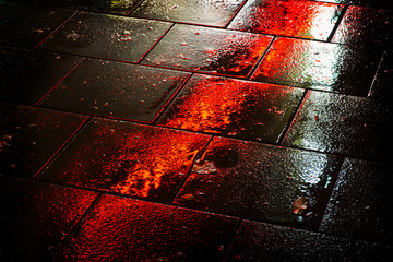 night reflection of light on the wet sidewalk of the city. reflection of red light.