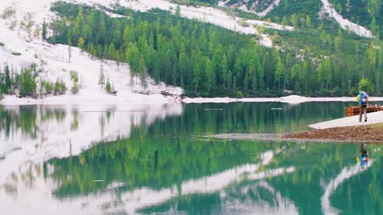 Wall Mural - young tourist hiker man at beautiful alpine lake lago di braies (pragser wildsee) in trentino. exult