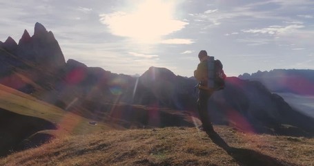 Wall Mural - aerial view. young man hiking at seceda mountain arriving to peak at sunrise. backpack, yellow jacke