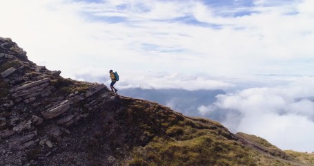 Wall Mural - aerial view. young man hiking at seceda mountain. backpack, yellow jacket, boots, beanie. traveling 