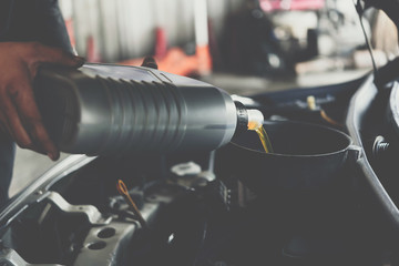 Car mechanic fills a fresh lubricant engine oil