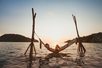 beach getaway, relaxation in hammock at sunset, paradise remote island holidays, happy man tourist r