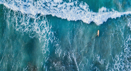 Wall Mural - surfer in the ocean top down aerial view in blue waves, banner background