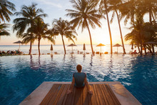 Summer Holiday Getaway In Luxury Beach Hotel, Tourist Relaxing Near Luxurious Swimming Pool At Sunset, Vacation On Tropical Island