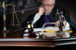 © zolnierek - Judge looking through legal code with the wooden gavel in his hand.