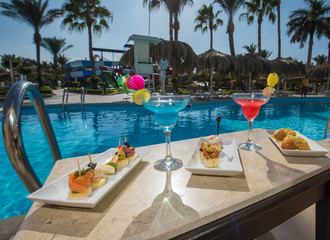 Cocktail drinks on table by a swimming pool of luxury hotel resort