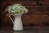 Fototapeta  - white bouquet of gypsophila in a white jug on a wooden, vintage background, interior