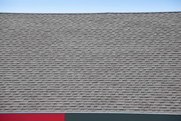 Poster - Roof shingles on top of the house against blue sky. dark asphalt tiles on the roof background.