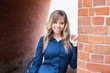 © Марина Демешко - A cute female student in a blue shirt with a beautiful smile stands on the background of a brick wall. Dressed in business style