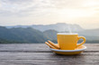 © saelim - A white cup of hot espresso coffee mugs placed with cookies on a wooden floor with morning fog and moutains with sunlight background,coffee morning