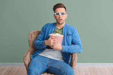 Poster - Handsome man watching movie while sitting in armchair near color wall