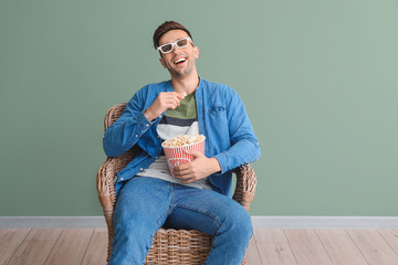 Canvas Print - Handsome man watching movie while sitting in armchair near color wall