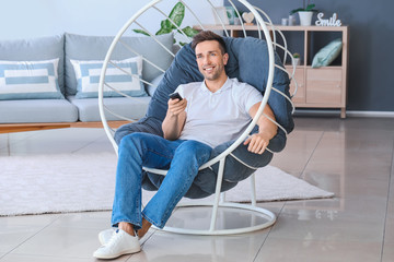 Poster - Handsome man watching TV while sitting in armchair at home