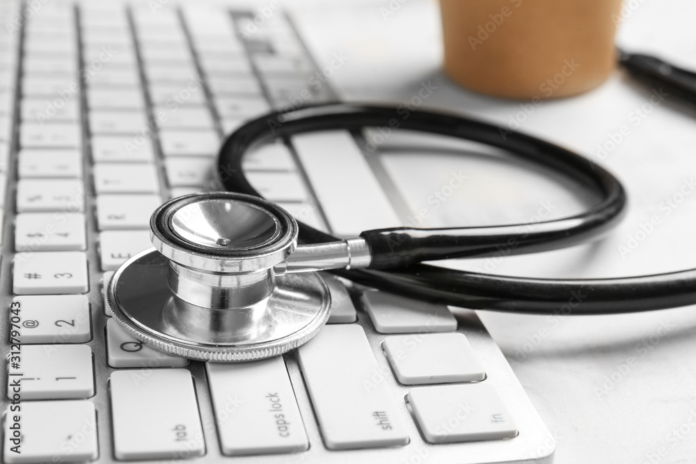 Stethoscope and PC keyboard on table, closeup