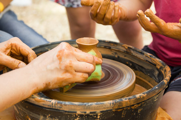 A close up view on ceramic production process on potter's wheel with children. Clay crafts with kids concept.