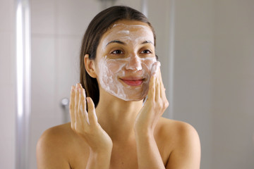 Skincare woman washing face  foaming soap scrubbing skin. Face wash exfoliation scrub soap woman washing scrubbing with skincare cleansing product. Enjoying relaxing time.