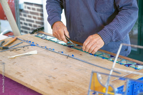 Fotografía A man artist collects small squares of glass mosaic