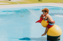 Adorable African Baby Boy Playing On Water Playground On A Hot Summer Day