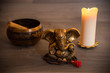 Yoga/Meditation Backgound - Golden Singing bowl, Ganesha Statue and Candle on Wooden Background. Selective Focus. Blurred Background Warm Light and Colours. Isolated Equipment.