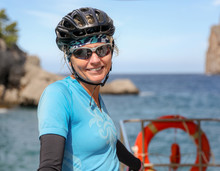 Woman Wearing Sunglasses And A Bike Helmet While On The Back Of A Boat. 