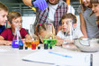 © gorynvd - Test tubes with colorful liquid substances. Study of liquid states. Group school pupils with test tubes study chemical liquids. Science concept. Girls and boy providing experiment with liquids.