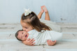 © Ursula Page - 3 year old big sister kissing her newborn little sister in a cool tone white room