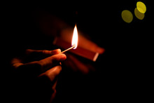 Man Holding A Burning Match Stick In The Dark Close Up.