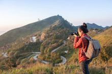 Tourist Woman Take A Photographs Of Beautiful Landscape Of Doi Pha Tang In Chiang Rai Province Of Thailand At Sunset. Doi Pha Tang Is A Mountain Cliff Over Thai-Laotian Border.