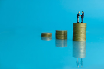 Miniature business concept - two businessman make an handshake for partnership agreement handshake with coin stack