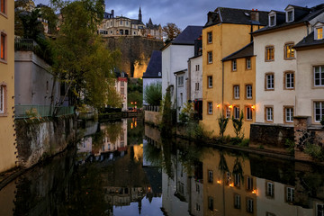 Wall Mural - Pastel houses reflecting in Alzette river in Luxembourg old town, UNESCO World Heritage Site and the city wall at sunset