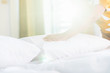 © SKT Studio - Hand of housekeeper set up white pillow on the bed sheet in hotel room at morning time with sunlight from windows