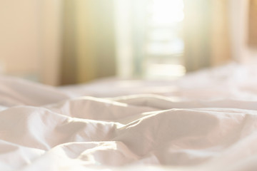 white bedding sheets and pillow in hotel room at morning time with sunlight from windows