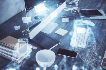 Desktop computer background in office and flying envelops hologram drawing. Multi exposure. Electronic mail concept.