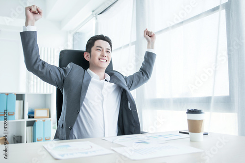 Portrait of excited Asian man holding hands folded in elbows and screaming in joy against white background Tableau sur Toile