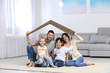 © New Africa - Happy family sitting under cardboard roof at home. Insurance concept