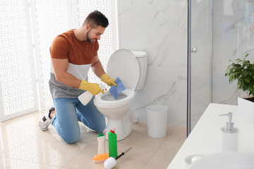 Sticker - Young man cleaning toilet bowl in bathroom