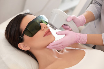 young woman undergoing laser epilation procedure in beauty salon