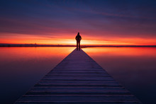 A Man Enjoying The Colorful  Dawn On A Jetty In A Lake. Groningen, Holland.